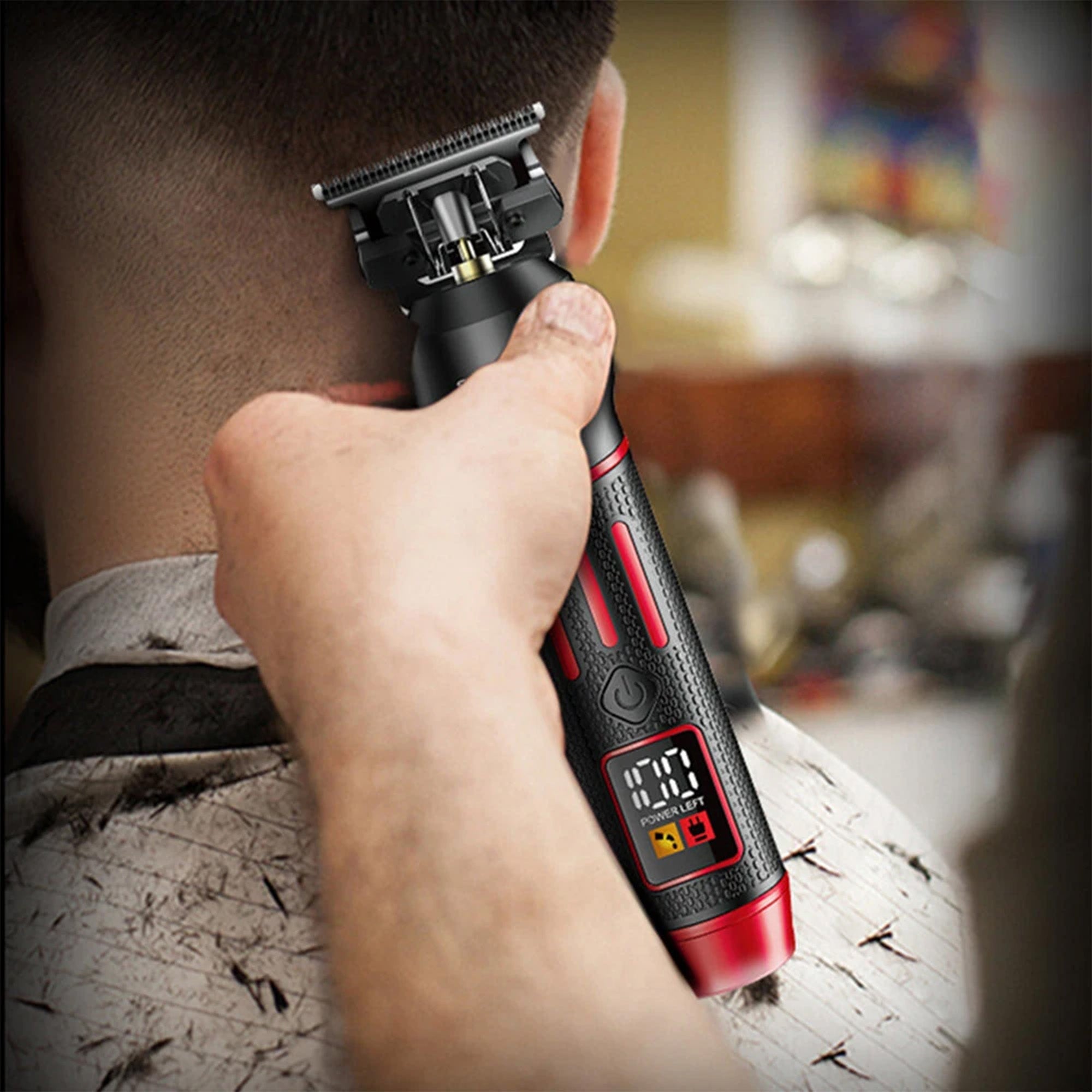 Person using a black and red electric razor with digital display on blurred background