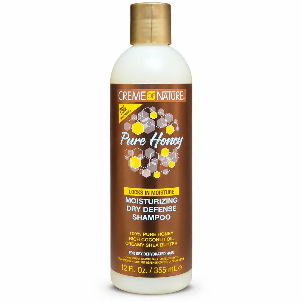 A bottle of Creme Nature Pure Honey Locks in Moisturizing Dry Defense Shampoo, featuring a brown label with honeycomb graphics and a gold cap, on a white background.